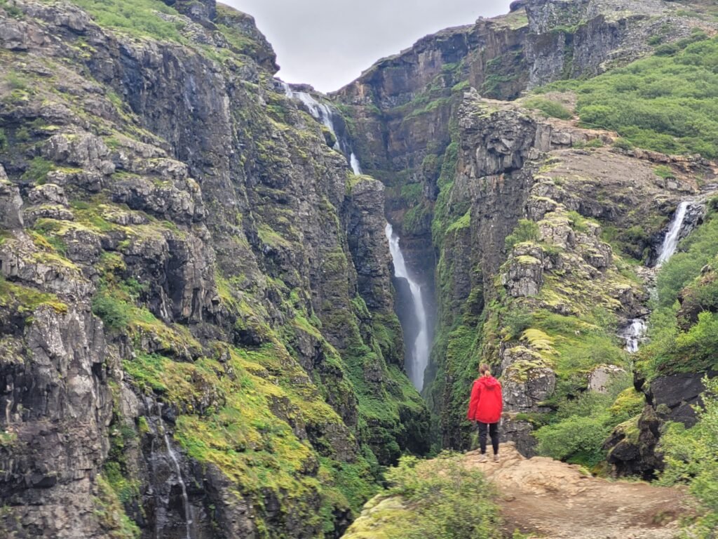 Girl standing looking at Glymur Waterfall